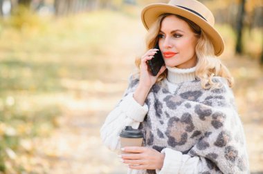Happy smiling young woman in park on autumn day