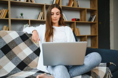 Woman freelancer working with laptop at home on sofa. Working girl portrait.
