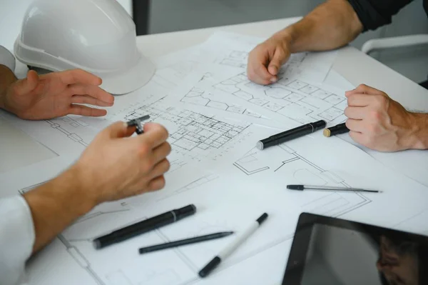 two people sit in front of construction plan and talk about the architecture.