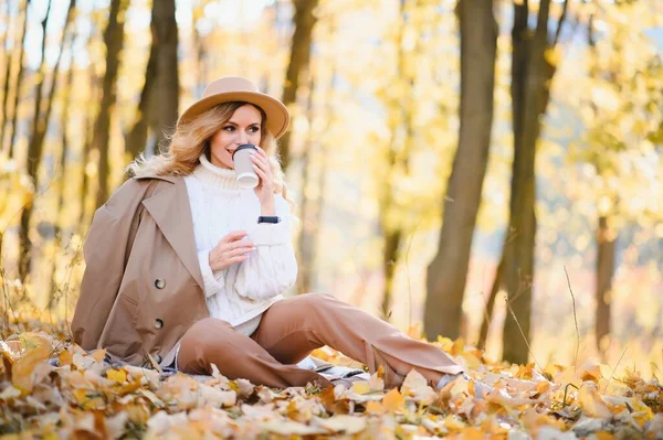 Happy smiling young woman in park on autumn day