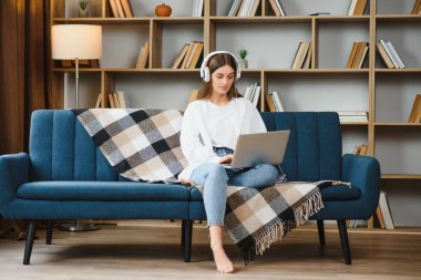 Woman freelancer working with laptop at home on sofa. Working girl portrait.