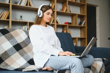 Woman freelancer working with laptop at home on sofa. Working girl portrait.