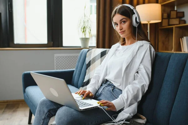 Woman freelancer working with laptop at home on sofa. Working girl portrait.