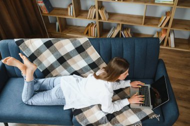 Woman freelancer working with laptop at home on sofa. Working girl portrait.