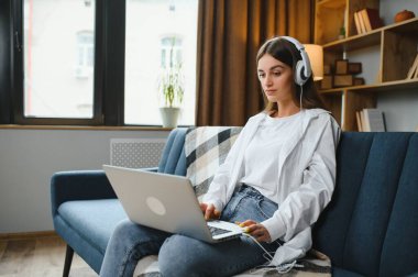 Woman freelancer working with laptop at home on sofa. Working girl portrait.