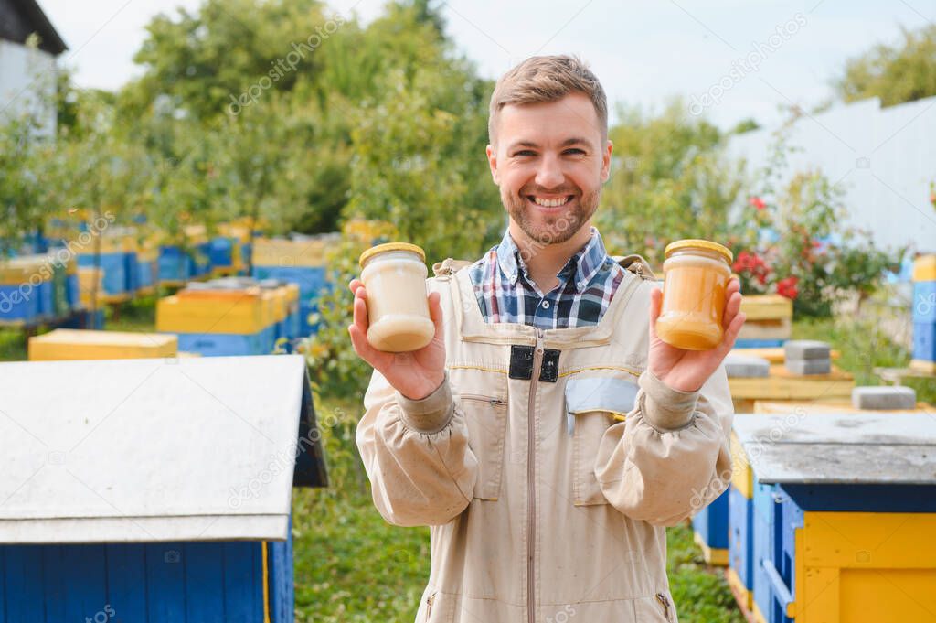Beekeeper with honey in jars at apiary.