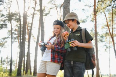 Happy excited school children with backpacks in casual clothes enjoying walk in forest on sunny autumn day, two active kids boy and girl running and playing together during camping trip in nature