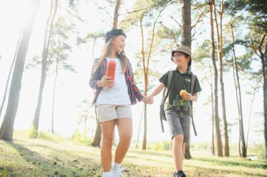 Küçük erkek ve kız bir orman yolu üzerinde yürüyüş gitmek.