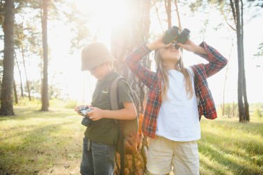Happy excited school children with backpacks in casual clothes enjoying walk in forest on sunny autumn day, two active kids boy and girl running and playing together during camping trip in nature