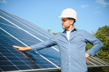 Young architect standing by solar panels.