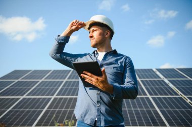 Young architect standing by solar panels.