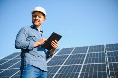 Young architect standing by solar panels.