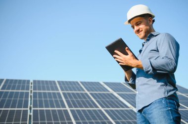 Young architect standing by solar panels.