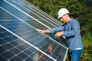 Worker technician connecting heavy solar photo voltaic panels to high steel platform. Exterior solar system installation, alternative renewable green energy generation concept.