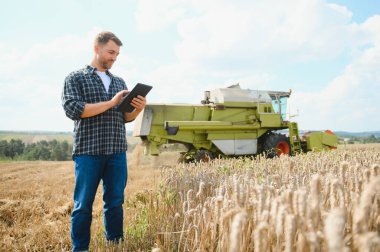 Tablet konumu önünde olan yakışıklı bir çiftçi hasat hasat alanında sırasında birleştirmek