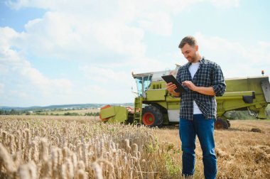 Tablet konumu önünde olan yakışıklı bir çiftçi hasat hasat alanında sırasında birleştirmek
