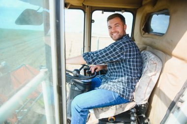 Çiftçi biçerdöveri kontrol ediyor.