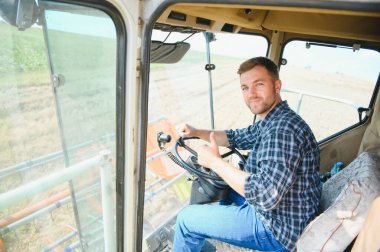 Çiftçi biçerdöveri kontrol ediyor.