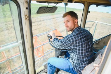 Çiftçi biçerdöveri kontrol ediyor.