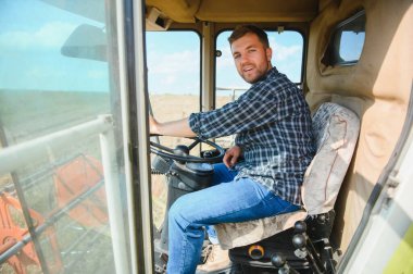 Çiftçi biçerdöveri kontrol ediyor.