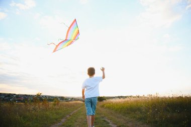 Çocuklar gün batımında sahada uçurtma fırlatırlar.