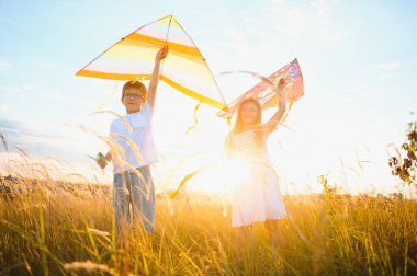 Çocuklar gün batımında sahada uçurtma fırlatırlar..