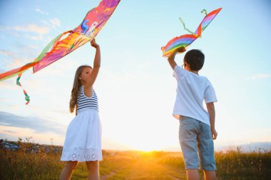 Mutlu çocuklar gün batımında sahaya uçurtma fırlatırlar. Küçük oğlan ve kız yaz tatilinde.