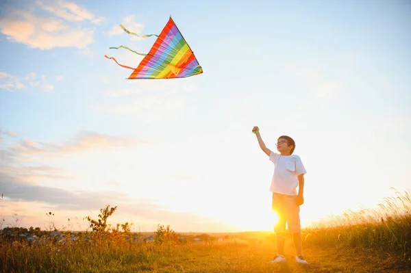 Boy is running with a kite during the day in the field.