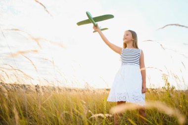 Happy kid with toy plane is playing at sunset.