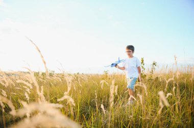 Mutlu çocuk mavi gökyüzü arka planında oyuncak uçakla oynuyor.