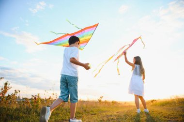 Mutlu çocuklar gün batımında sahaya uçurtma fırlatırlar. Küçük oğlan ve kız yaz tatilinde.