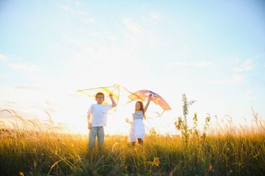 Çocuklar gün batımında sahada uçurtma fırlatırlar..