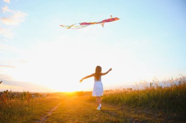 doğada yaz aylarında çayır üzerinde çalışan bir uçurtma ile kız mutlu çocuk.