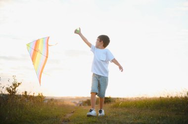 Çocuklar gün batımında sahada uçurtma fırlatırlar.