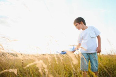 Mutlu çocuk mavi gökyüzü arka planında oyuncak uçakla oynuyor.
