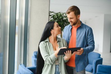 Smiling businesspeople work collaborate on computer, brainstorm over company startup at office meeting. Motivated diverse colleagues look at laptop screen discuss business project ideas together.