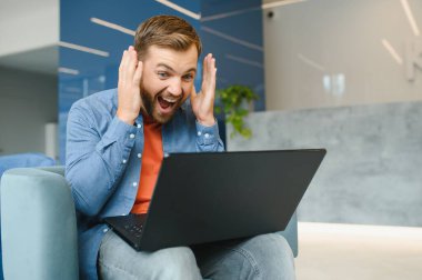 Heyecanlı genç adamın fotoğrafı. Mutlu mutlu gülümseme. Zaferi kutla.