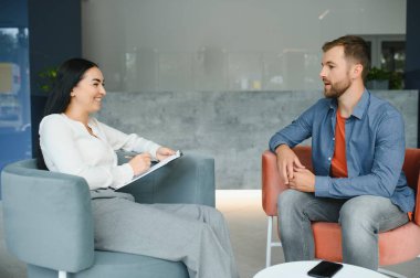 Psychologist talking with patient on therapy session. Depressed man speaking to a therapist while she is taking notes