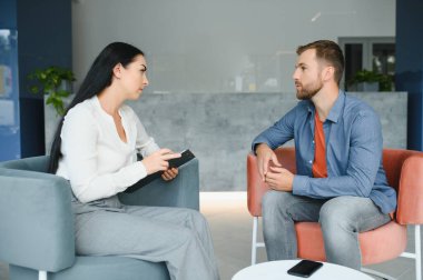 psychology, mental therapy and people concept - woman psychologist talking to sad young man patient at psychotherapy session