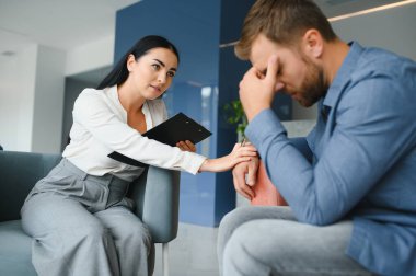 psychology, mental therapy and people concept - woman psychologist talking to sad young man patient at psychotherapy session