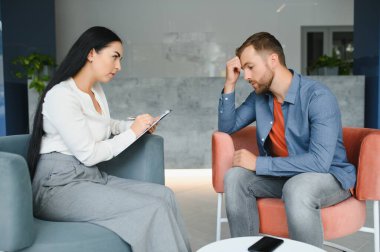 Depresyon danışmanlığı. Ofiste randevu sırasında profesyonel psikolog not alırken umutsuz bir adam mutsuz bir hayatı anlatıyor. Seçici Odaklanma.