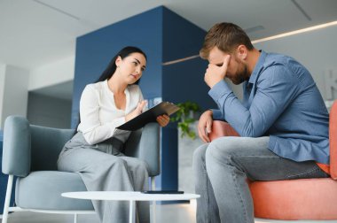 Depresyon danışmanlığı. Ofiste randevu sırasında profesyonel psikolog not alırken umutsuz bir adam mutsuz bir hayatı anlatıyor. Seçici Odaklanma.