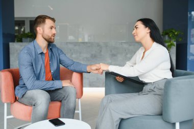 Psychologist talking with patient on therapy session. Depressed man speaking to a therapist while she is taking notes
