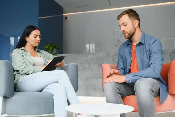 psychology, mental therapy and people concept - woman psychologist talking to sad young man patient at psychotherapy session