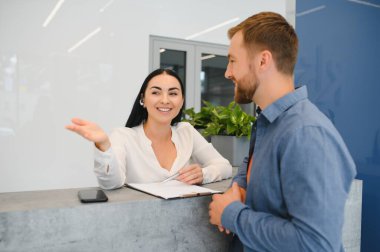 Resepsiyonda dururken müşteriile konuşan hoş bir dost kadın