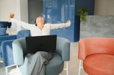 Kanepe oturma ve laptop ile iş merkezi bekleme salonunda çalışan genç iş kadını.