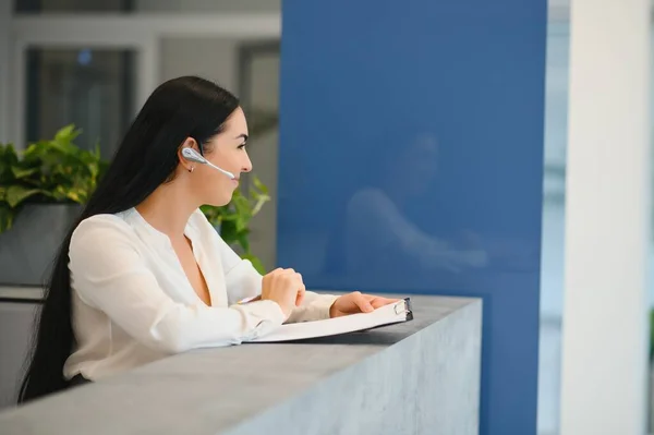 Portrait of beautiful receptionist near counter in hotel.