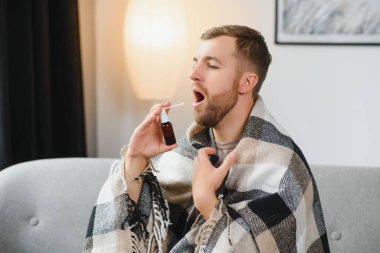 Rhinitis, ilaç ve sağlık konsepti - evde ağız spreyi kullanan hasta adam.