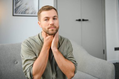 Boğaz ağrısı. Koyu saçlı genç adamın boğazı ağrıyor.