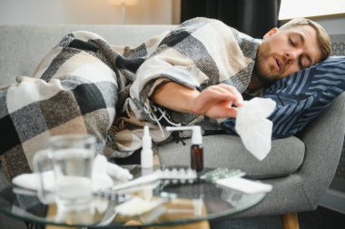 Kışın evde hava soğuktur. Kırık termostat yüzünden kışın evinde donan adam. Oturma odasındaki kanepede otururken yün ekoseye sarılı genç adam titriyor..